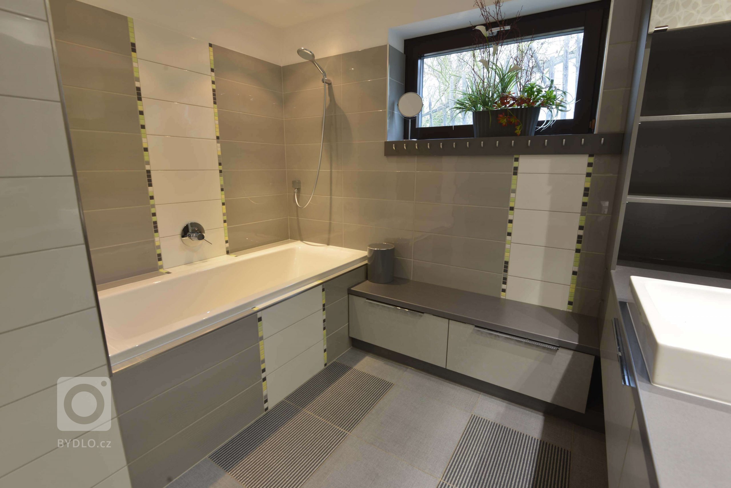 Na vanu navazuje lavice s úložným prostorem umožňující posazení dětí při svlékání a zavěšení ručníků a oblečení. 