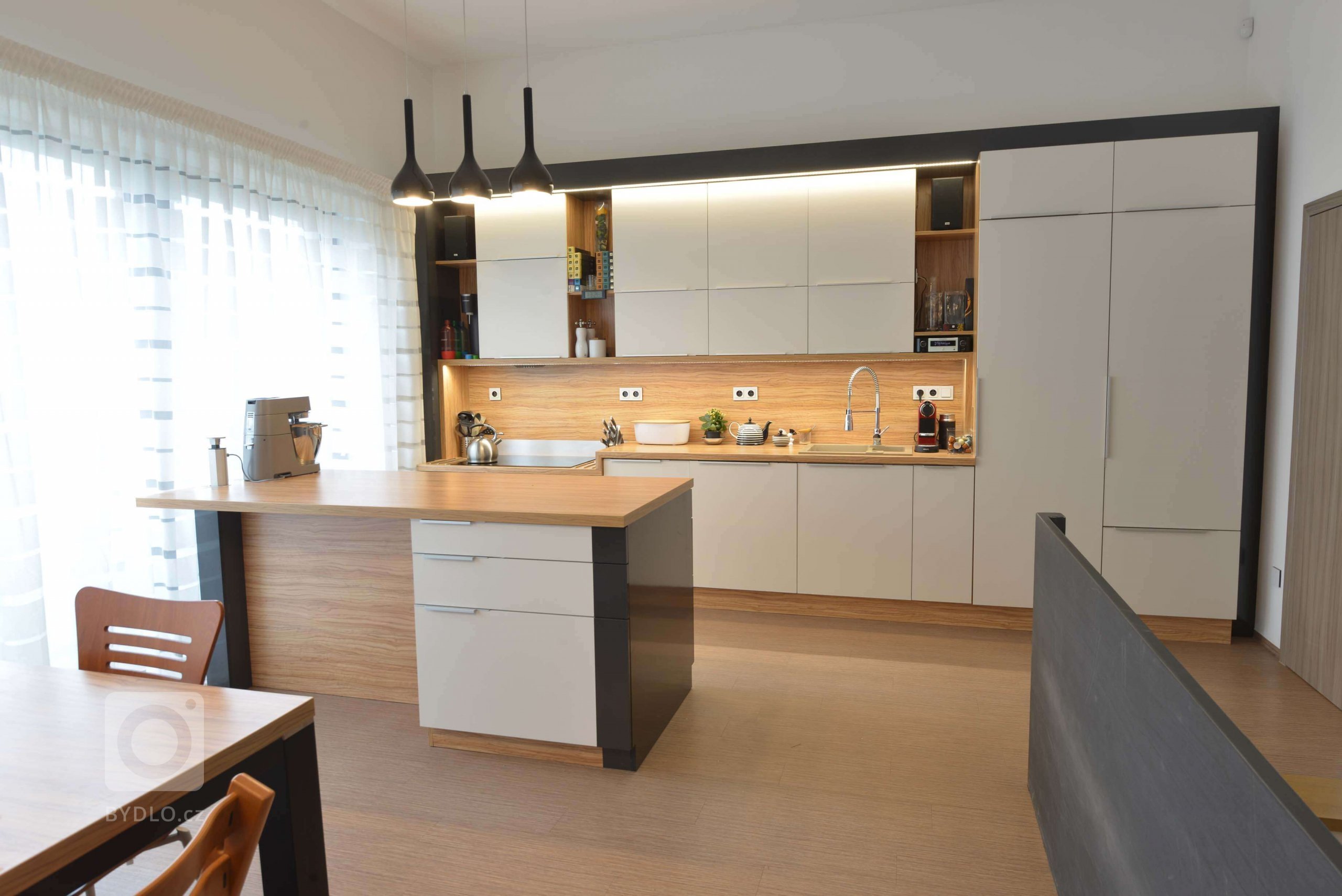 Kuchyně je trochu technická a střízlivá. Celý prostor je v kombinaci, černé lesklé s bílou matnou a dřevodekorem oliva. 