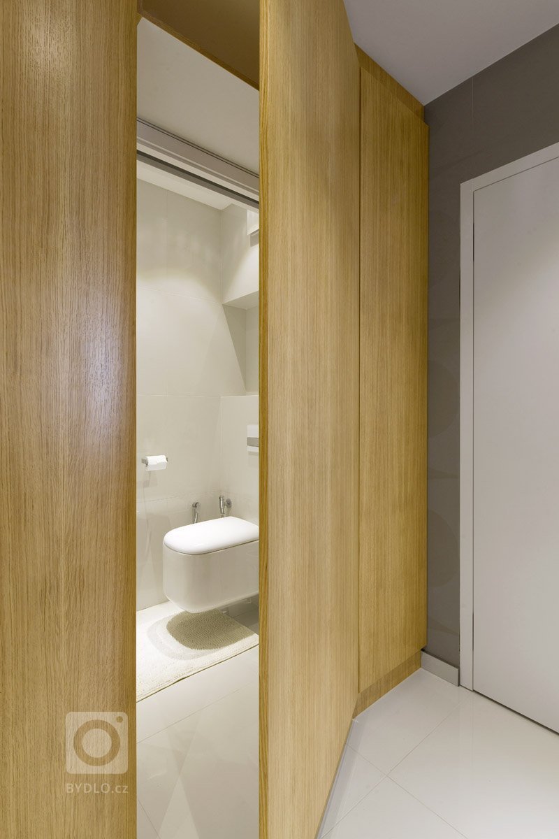 Rekonstrukce panelového bytu v odstínech dřeva a bílé.
