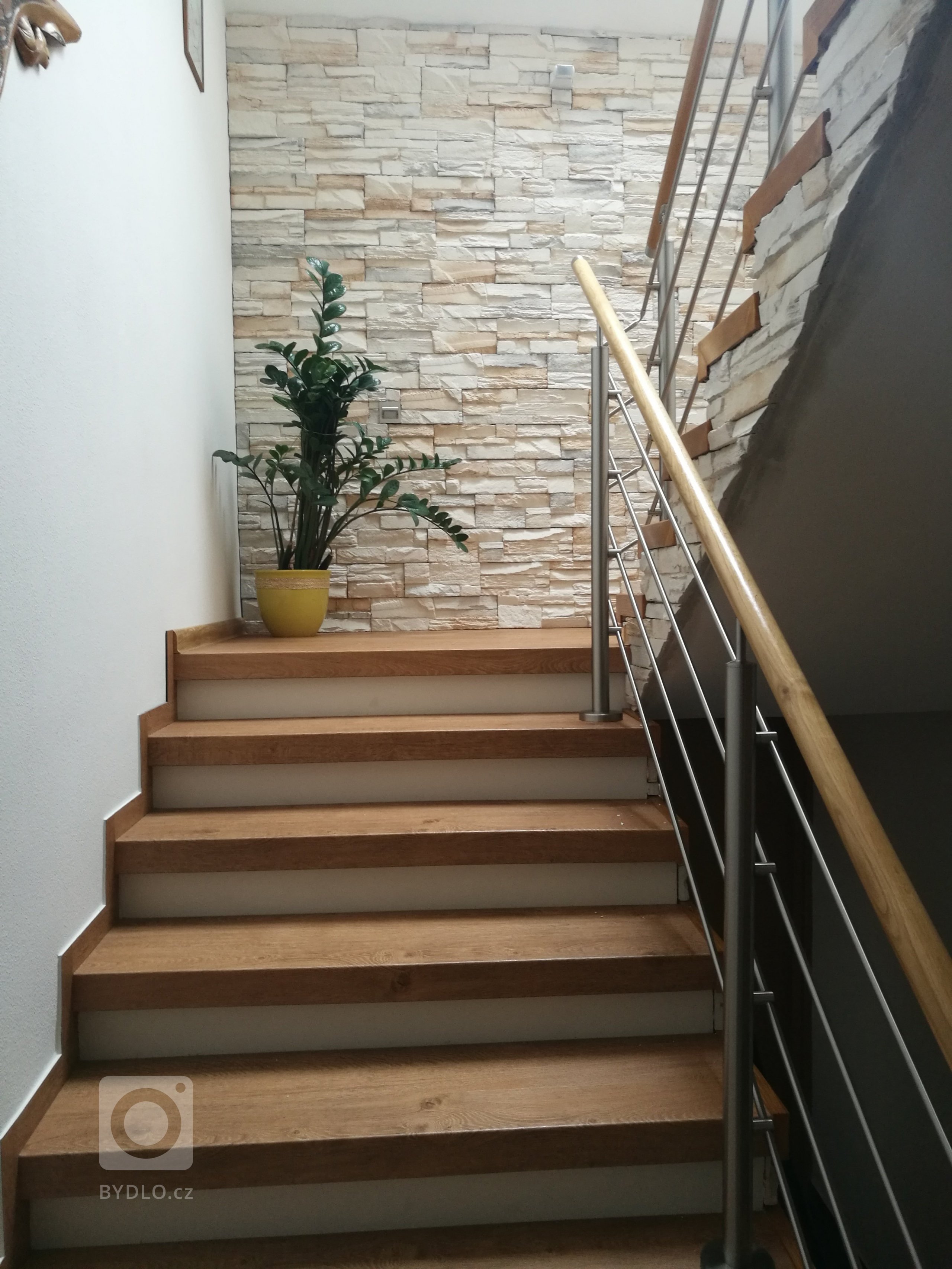 Obklad z umělého kamene hezky ladí s dekorem vinylové podlahy Bukoma na schodových nášlapech