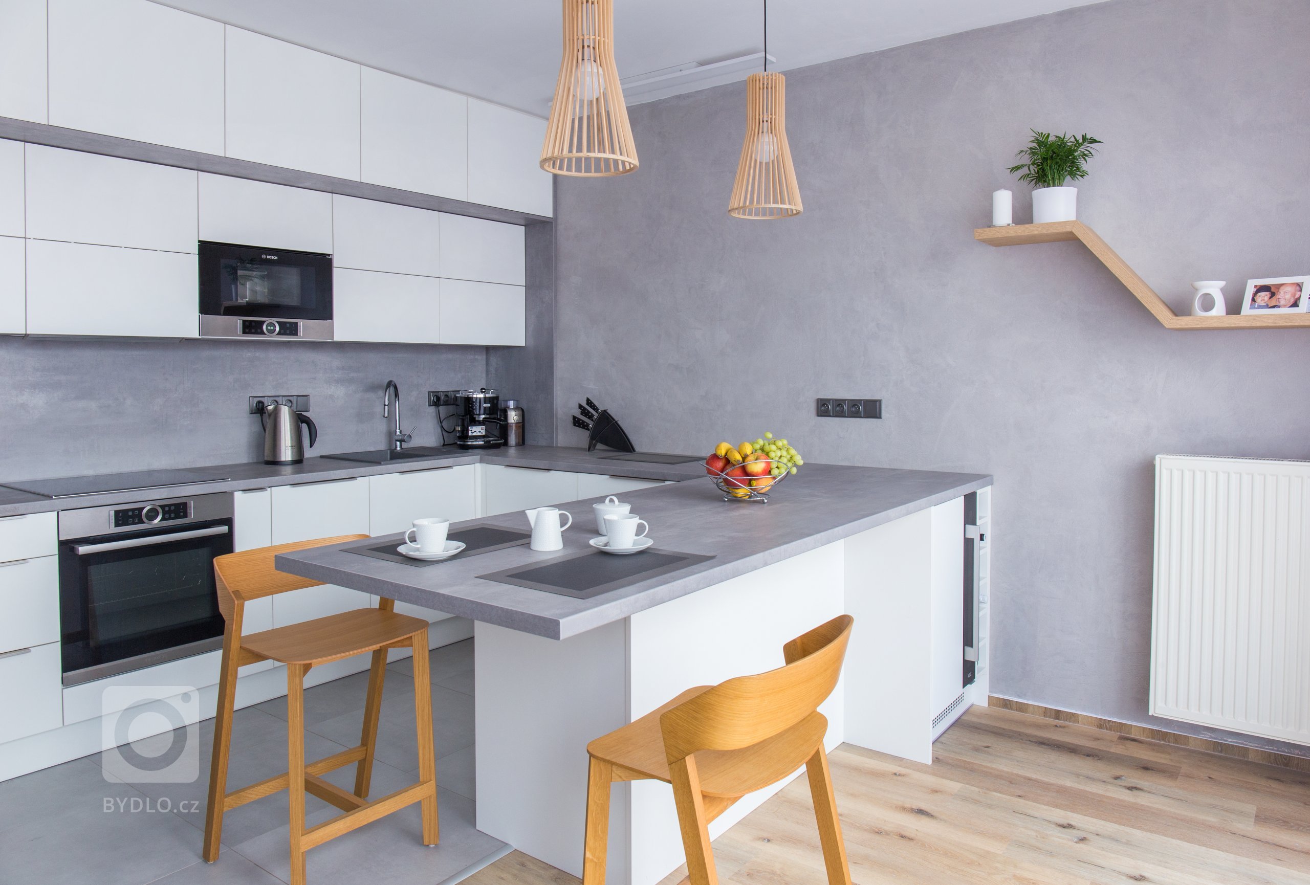 Byt 2+kk. Přáním klientky byla velká kuchyň s barovým posezením, vinotéka, skrytý bar, potravinová skříň a vyřešení úložných prostor. Jako vzpomínku chtěla mít…