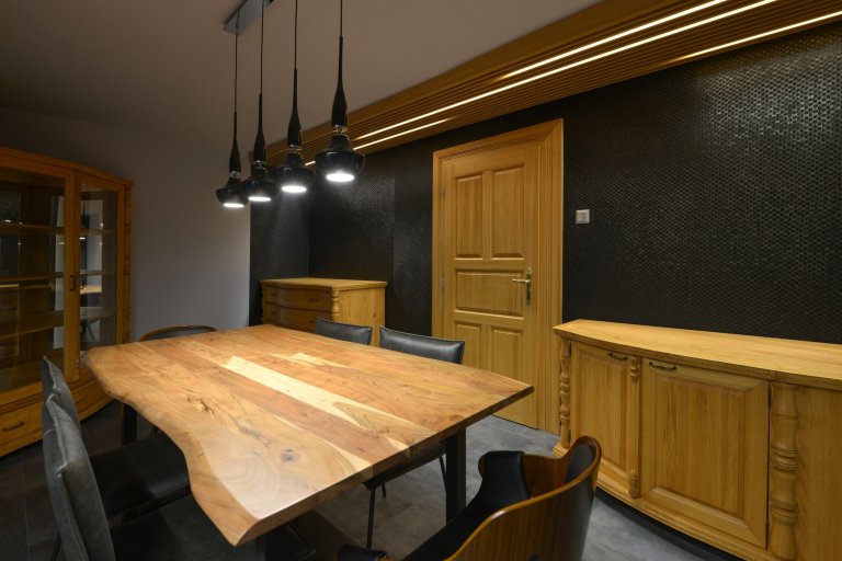 Pohled na dveře do jídelny s novým stropním roštem a osvětlením LED. Jídelna byla doplněna o nový jídelní stůl s masivní deskou , nové židle v černém provedení a závěsné osvětlení nad stůl. 