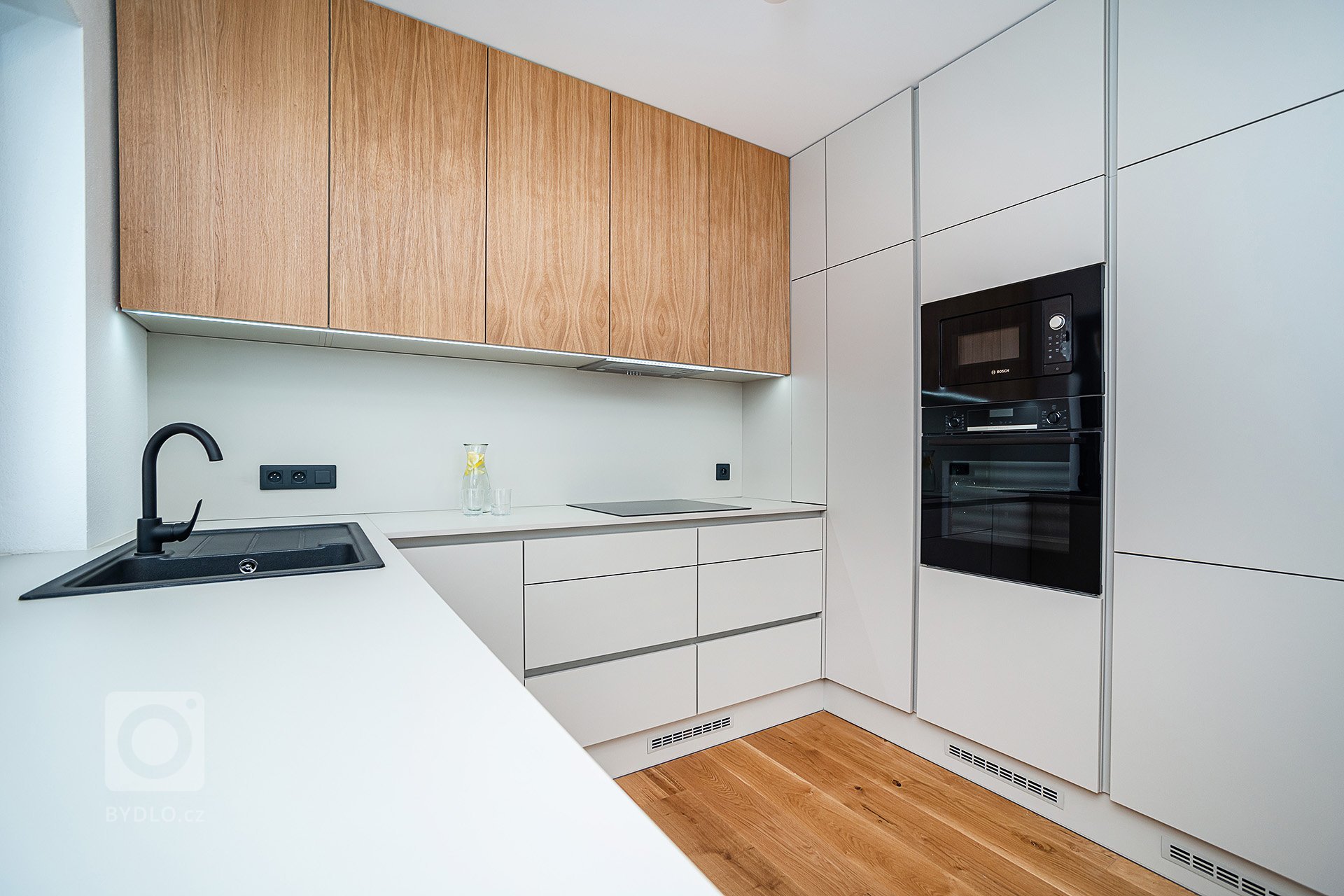 Interiér rodinného domu byl navržen v kombinaci olejovaného dubu, laminátu v odstínu taupe,&nbsp;černého lakovaného kovu a šedých odstínech velkoformátové…