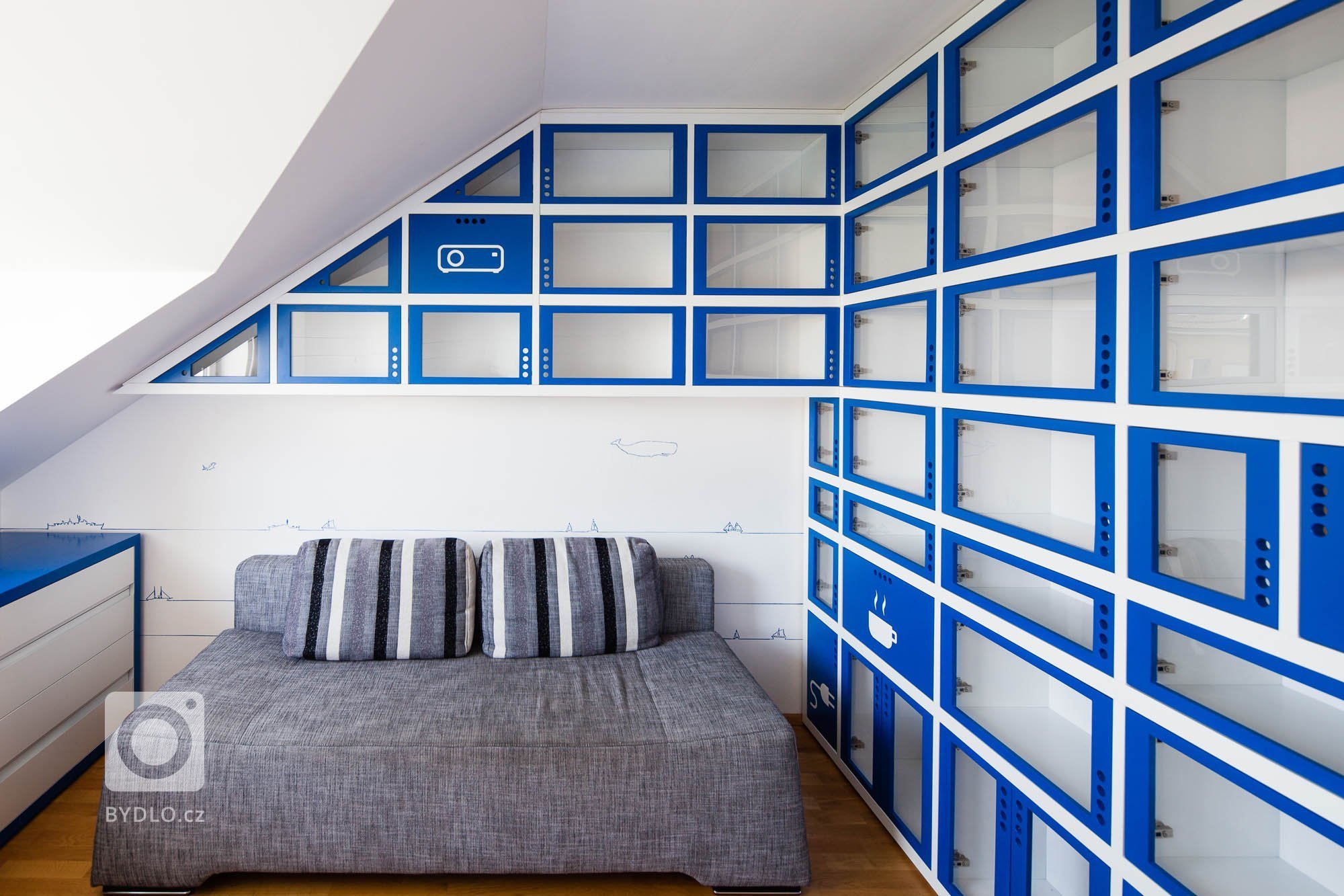 Zadáním byla pracovna v námořnickém stylu. Typickou modro-bílou kombinaci barev doplňuje neutrální šedá barva sedacího nábytku a přírodní barva dřeva podlahy a…