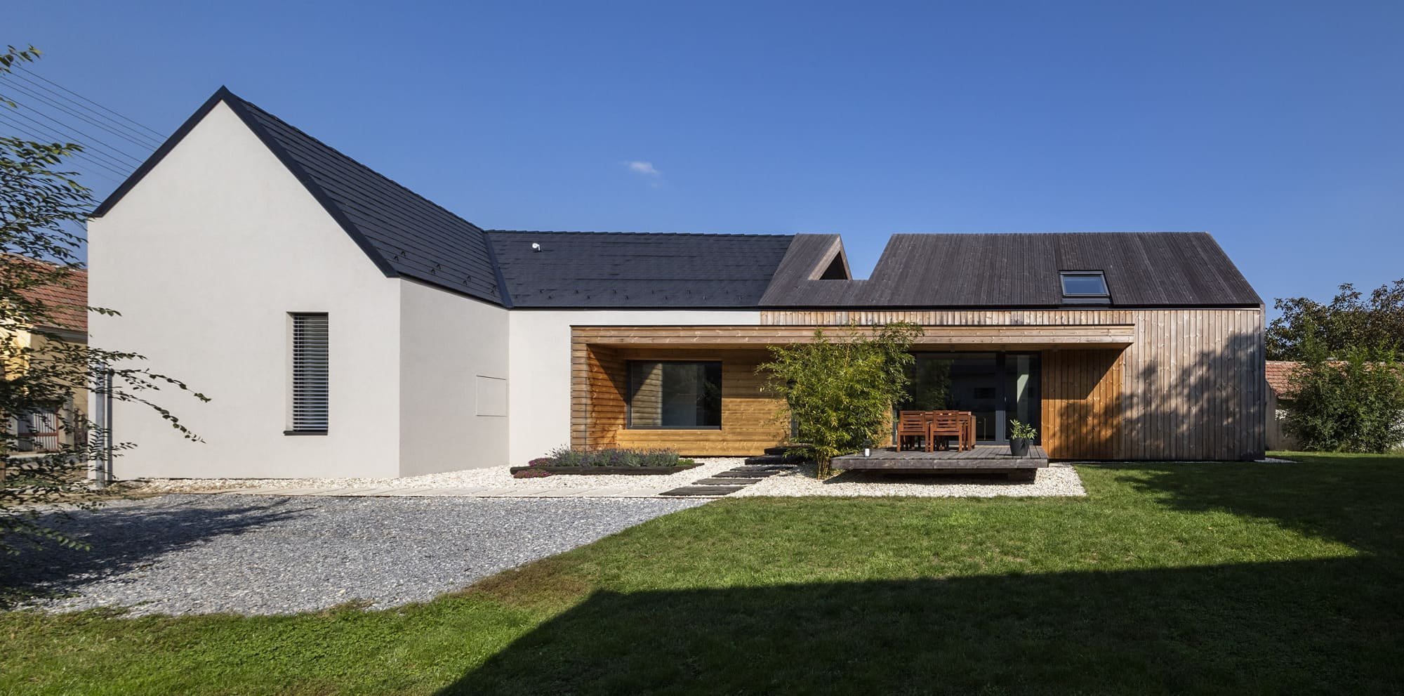 Nová část stavení má velká okna, která propojuje interiér se zahradou