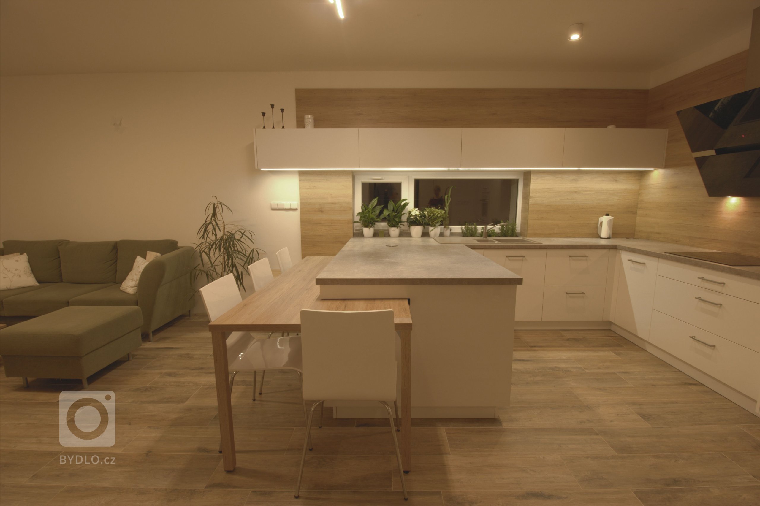 Vize klientky byla jasná, kuchyň s&nbsp;vysokým dřevěným obkladem a vybíhající horní bílá skříňka.

Kuchyně je ve tvaru U a na ní navazující stůl. Stůl je…