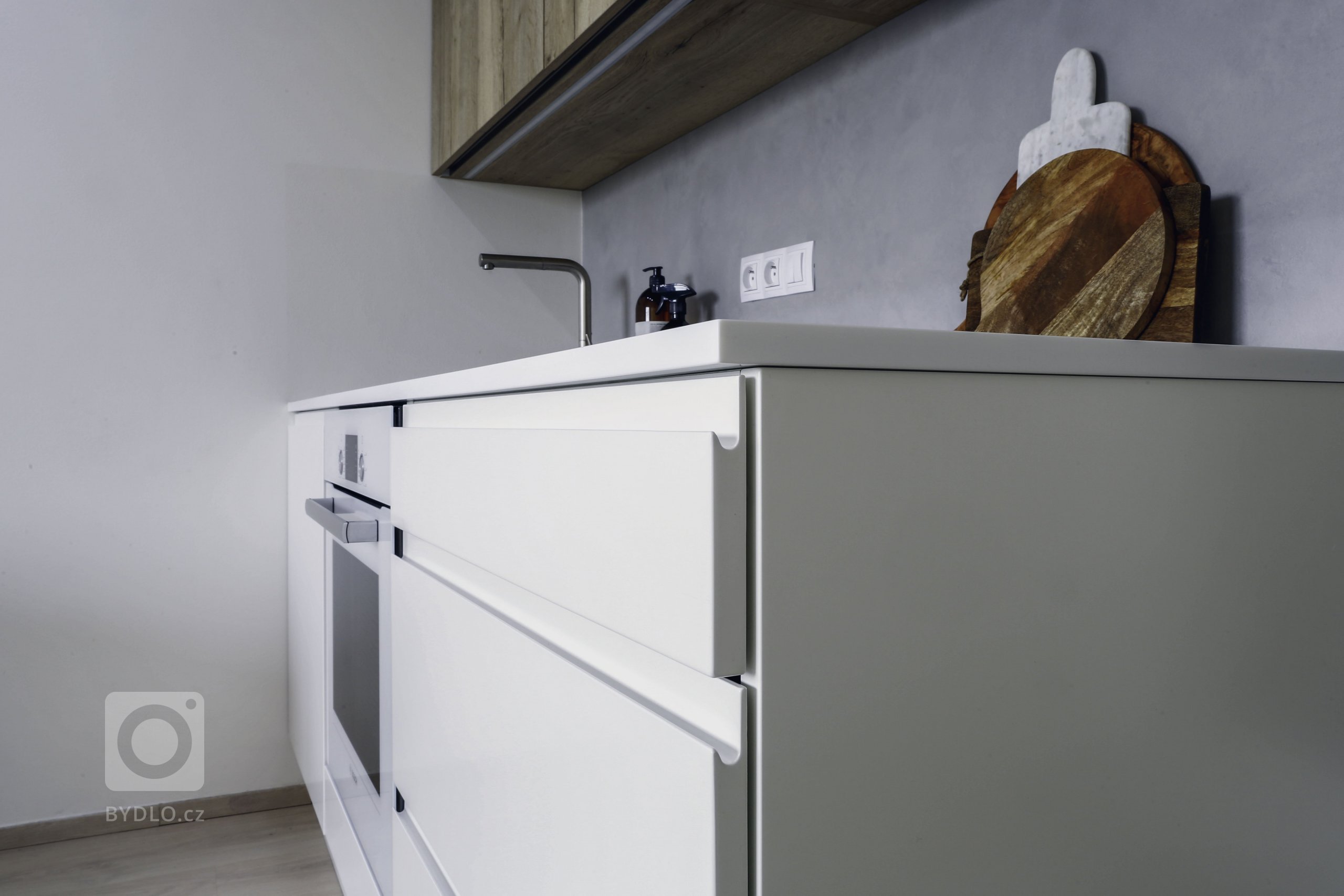 Kuchyně v malém bytě byla navržena tak, aby poskytla klientce dostatek úložných prostor nejen pro kuchyň, ale i pro další věci. Barvy i materiály byly vybrány…