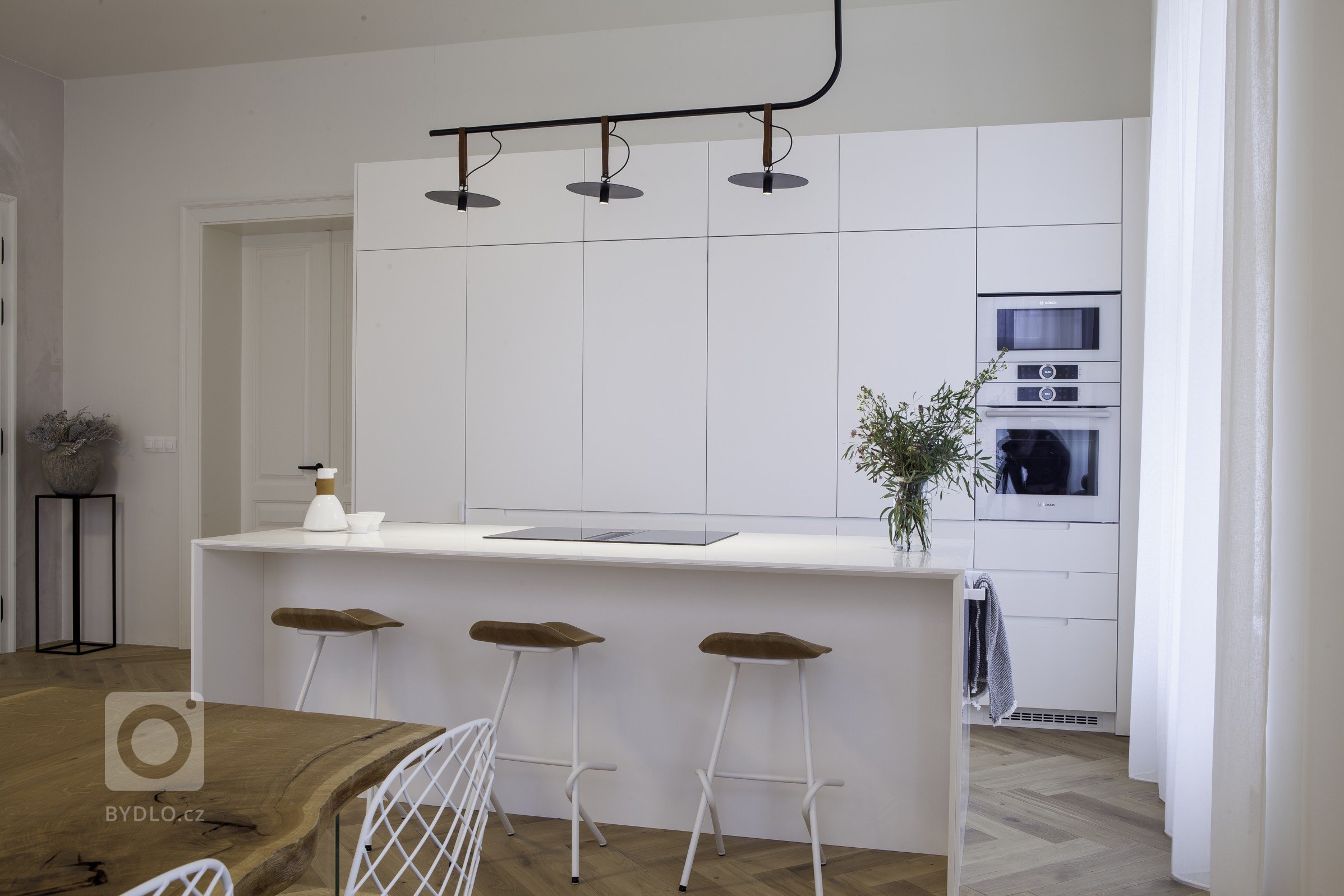 Kuchyňská linka s&nbsp;velkorysým ostrůvkem z materiálu Corian. Netradičním prvkem kuchyně je uzavíratelná část linky, díky které bude kuchyň vypadat uklizeně…