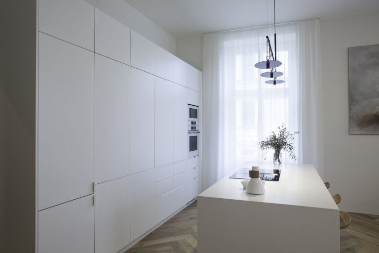 Kuchyňská linka s&nbsp;velkorysým ostrůvkem z materiálu Corian. Netradičním prvkem kuchyně je uzavíratelná část linky, díky které bude kuchyň vypadat uklizeně…