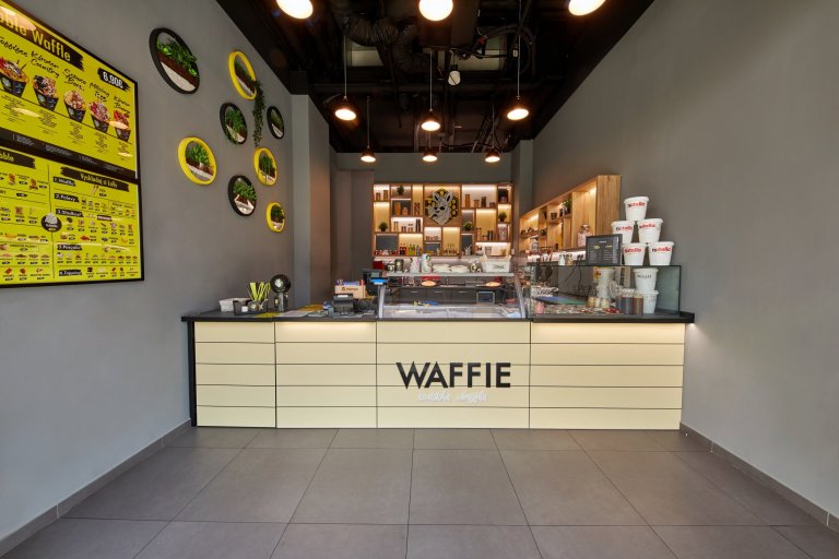 Zrealizovaný projekt prevádzky&nbsp;Waffie&nbsp;v nákupnom centre Eurovea v Bratislave. Kontrastné farebné kombinácie, doplnky, osvetlenie a samotné wafle…