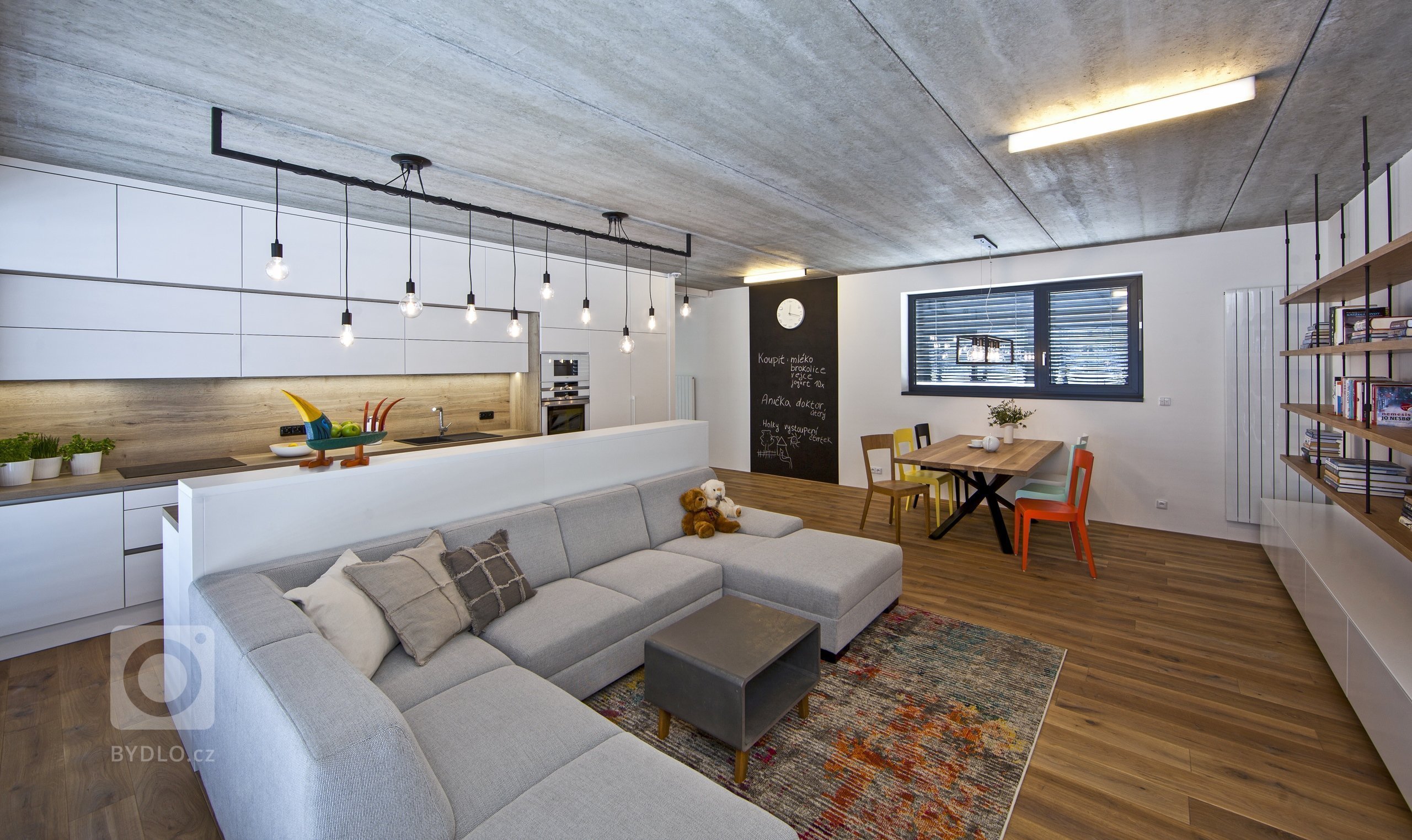 V celém domě se prolínají přírodní materiály s černými kovovými prvky a detaily s bílými stěnami a dveřmi. Industriální ráz podtrhují přiznané betonové stropy…