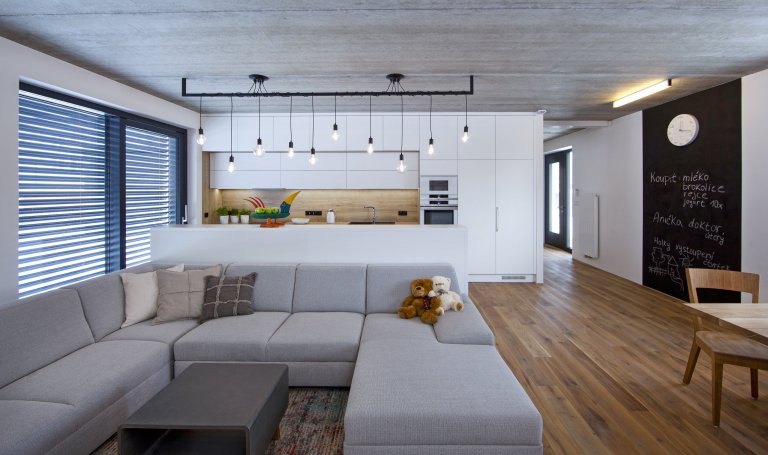 V celém domě se prolínají přírodní materiály s černými kovovými prvky a detaily s bílými stěnami a dveřmi. Industriální ráz podtrhují přiznané betonové stropy…