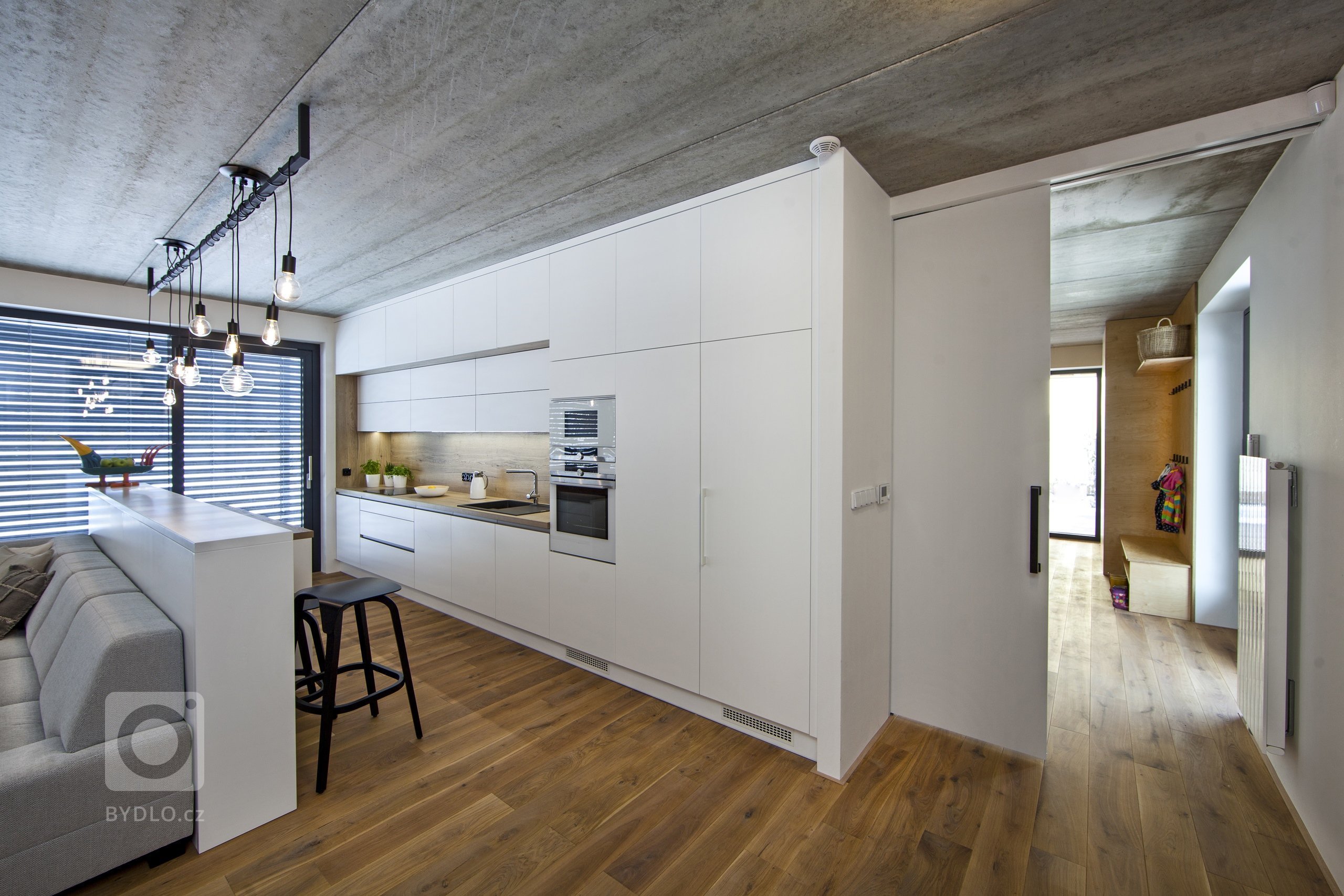 V celém domě se prolínají přírodní materiály s černými kovovými prvky a detaily s bílými stěnami a dveřmi. Industriální ráz podtrhují přiznané betonové stropy…