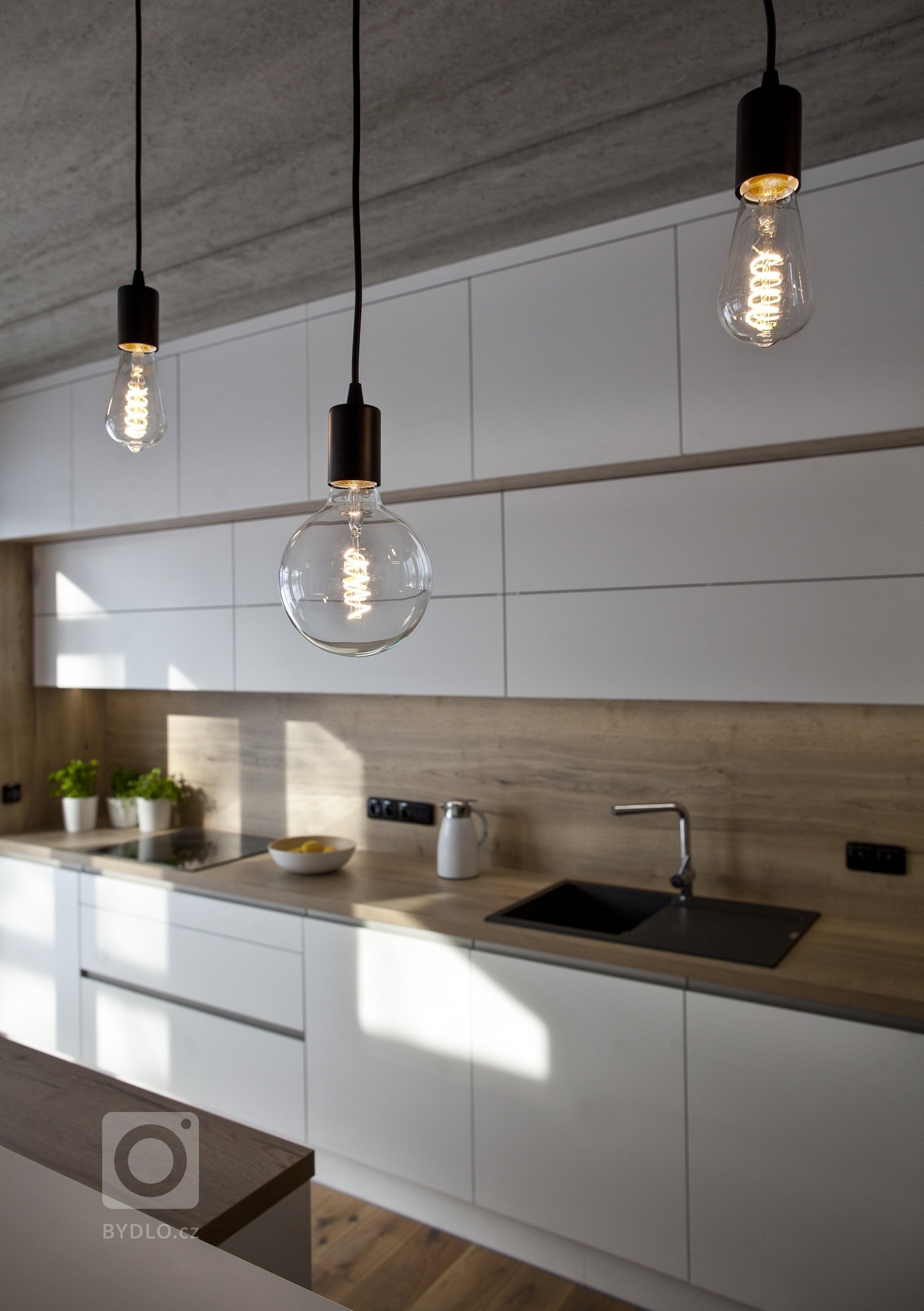 V celém domě se prolínají přírodní materiály s černými kovovými prvky a detaily s bílými stěnami a dveřmi. Industriální ráz podtrhují přiznané betonové stropy…