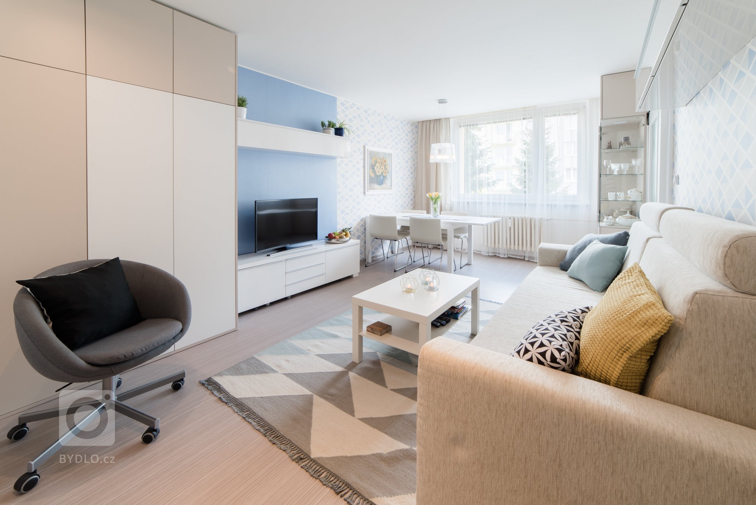 Původní velmi tmavý obývací pokoj se novým bílo-modro-béžovým laděním proměnil v příjemně světlý, svěží prostor. Výrazné tapety a koberec s pastelovými vzory…