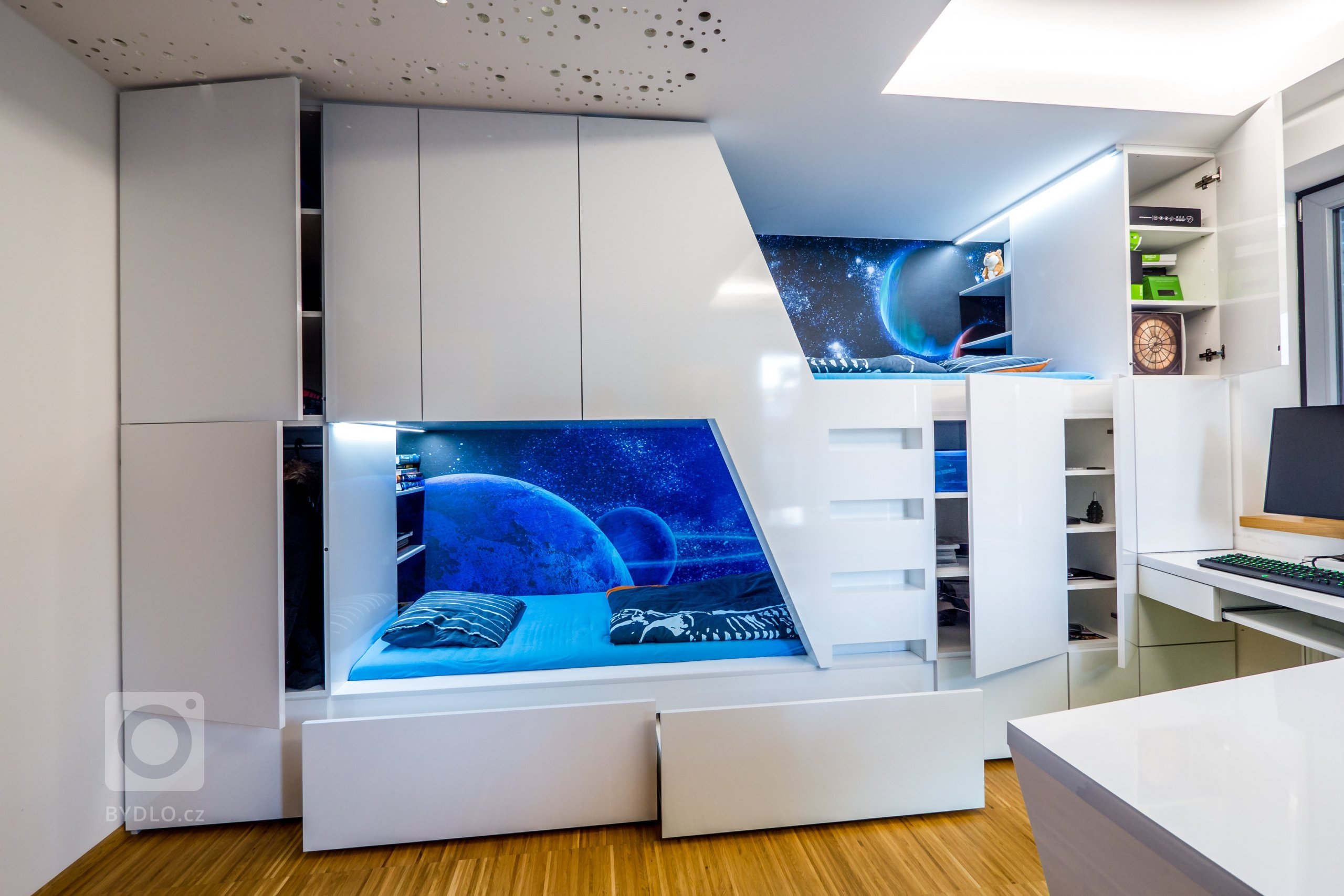 Dostaly postele a skříně v jednom balení... čímž se uvolnil zbytek pokoje na hraní a na práci. Stropní překlad, který nehezky půlil místnost na poloviny jsme šikovně zamaskovali sádrokartonem. Na levé polovině mají kluci jemné noční osvětlení jako hvězdné nebe a na pravé polovině výkonné stmívané osvětlení nad pracovní stoly.