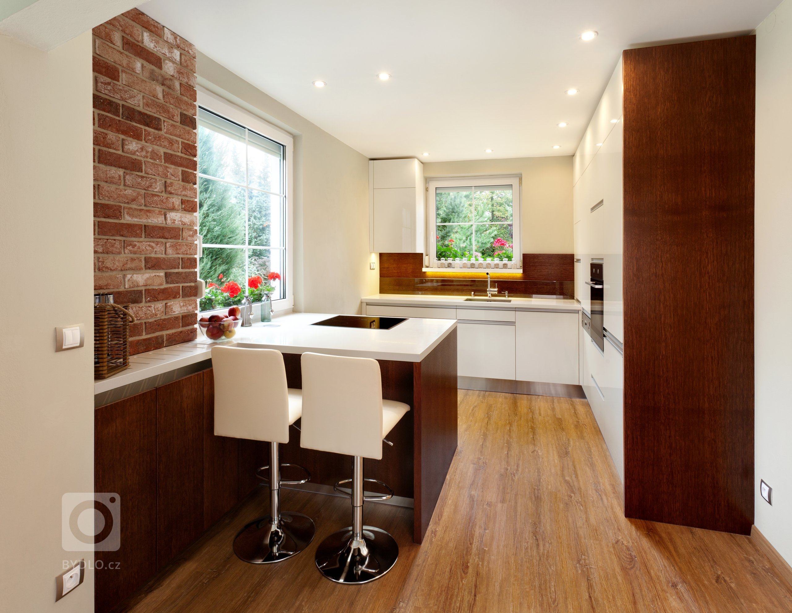 Představujeme vám malebnou kuchyň, která kombinuje moderní bílé povrchy s&nbsp;teplými tóny dubového dřeva. Přestože místnost není zrovna prostorná, i tak se…