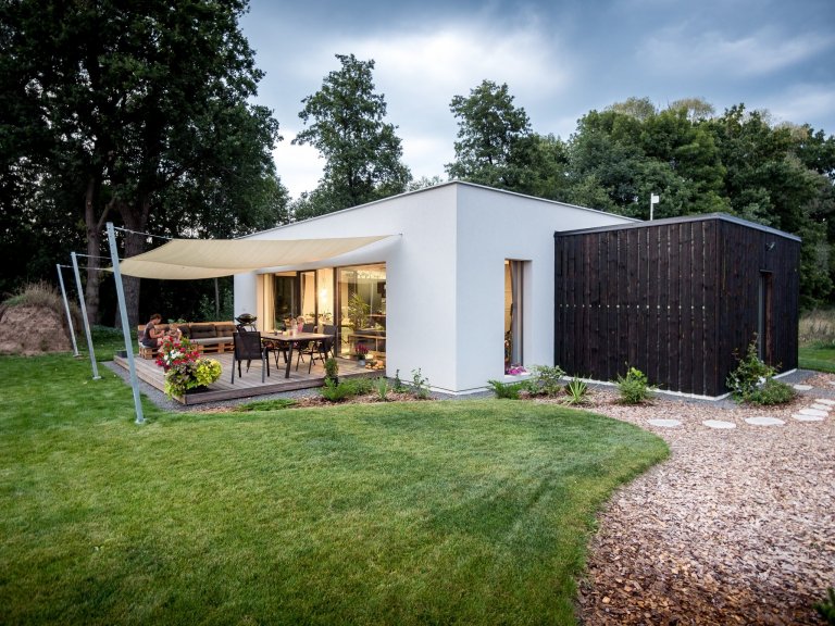 Základní hmotu domu ZEN HOME doplňuje přístavba z černých nesámovaných prken a výrazné textilní stínění terasy.